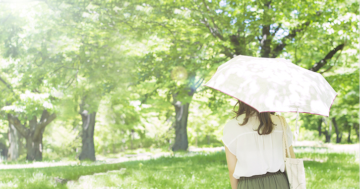 陽が差し込む森林の中で日傘を差しながら歩く女性のイメージ図
