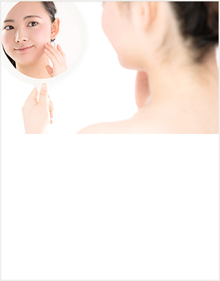 鏡をのぞきこみながらにきびを気にしている女性のイメージ写真