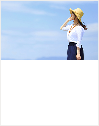 雲のある夏の終わりの空と、帽子をかぶった横向きの女性のイメージ写真