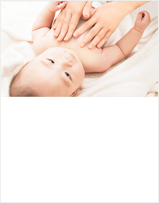 白い布の上に寝ている赤ちゃんと、赤ちゃんのお肌に手のひらをあてて赤ちゃんスキンケアをしているお母さん。穏やかなスキンケアタイムを過ごす親子の画像。