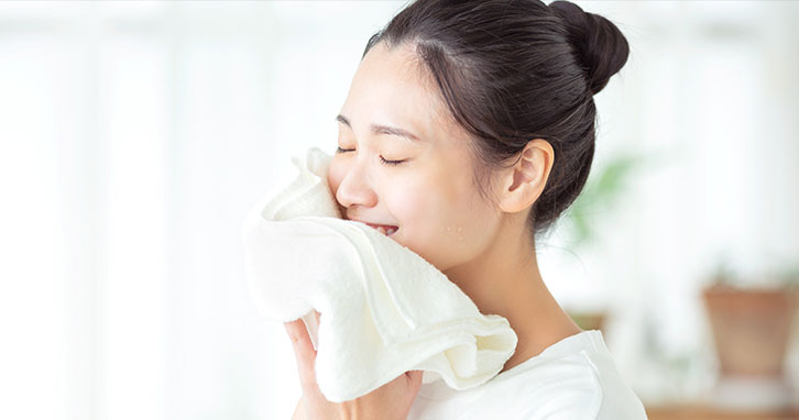 洗顔をしているにきび肌の女性の写真。にきびの原因となる毛穴のつまり・黒ずみを洗い流すマイルドピーリング作用のある洗顔料を使用し、にきびを防いでいる。