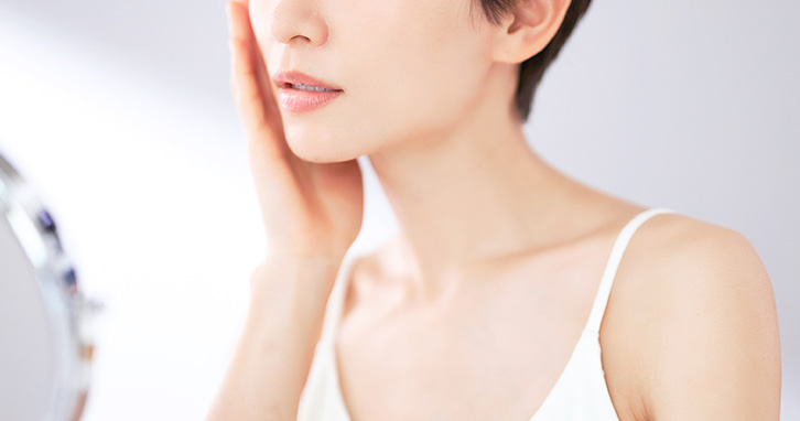 鏡を見ている女性の写真。乾燥しやすい敏感なお肌では役割の異なる保湿剤を重ねて使うことが大切です。